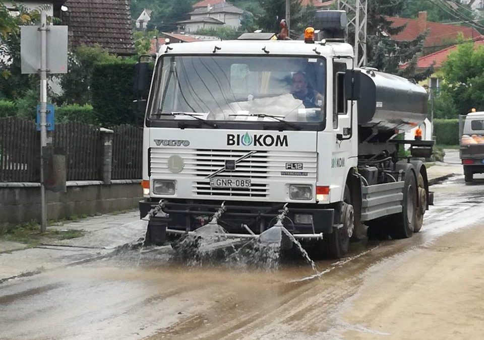 Egy fehér teherautó vizet permetez az utcára.